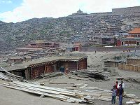 Panorama view of the center of the Larung Gar [bla rung gar] religious settlement with the Gyutrul Temple [sgyu 'phrul lha khang] (left) and Visitors Hostel (right) atop the ridge in back.